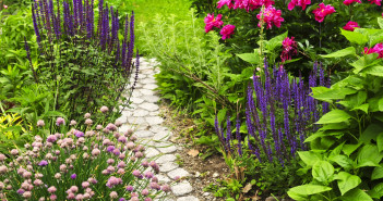 A pretty stone path with several kinds of flowers running along both sides of it.